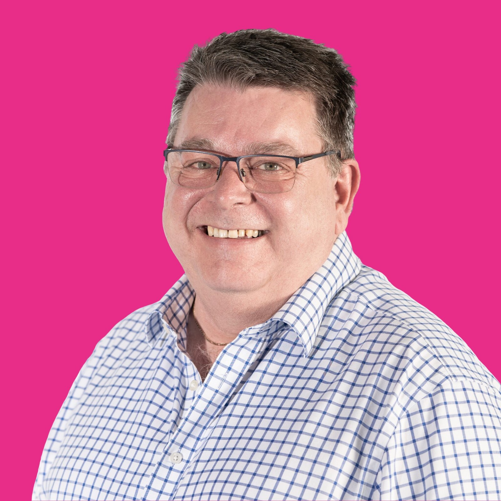 Headshot of male in shirt on pink background.