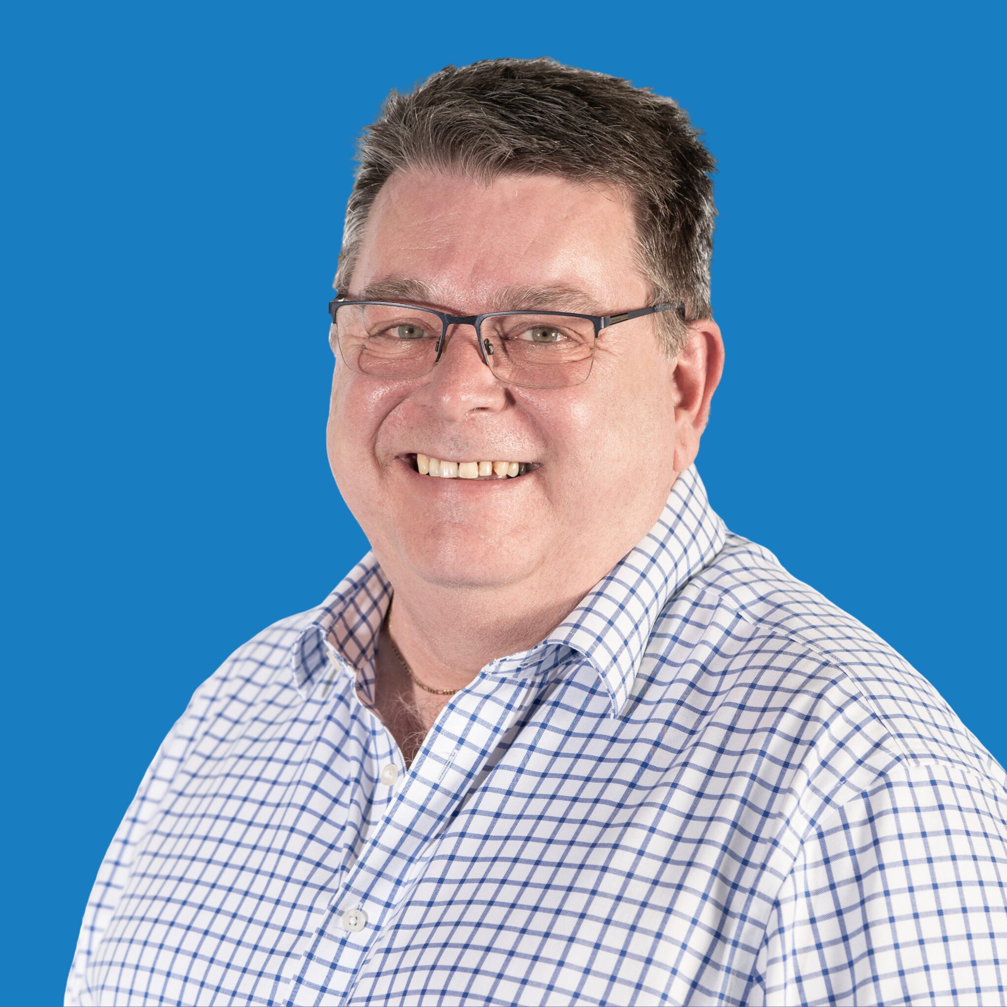 A portrait shot of a man in a shirt on a blue background.