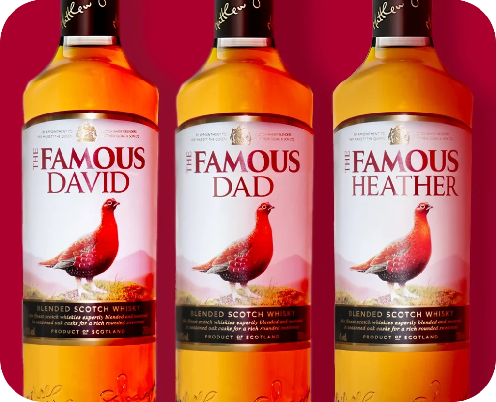 Three personalised bottles of The Famous Grouse whisky on a red background.