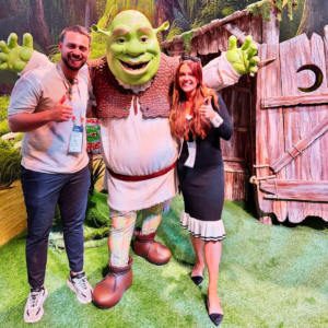 An image of a man and a woman stood next to a mascot of Shrek.