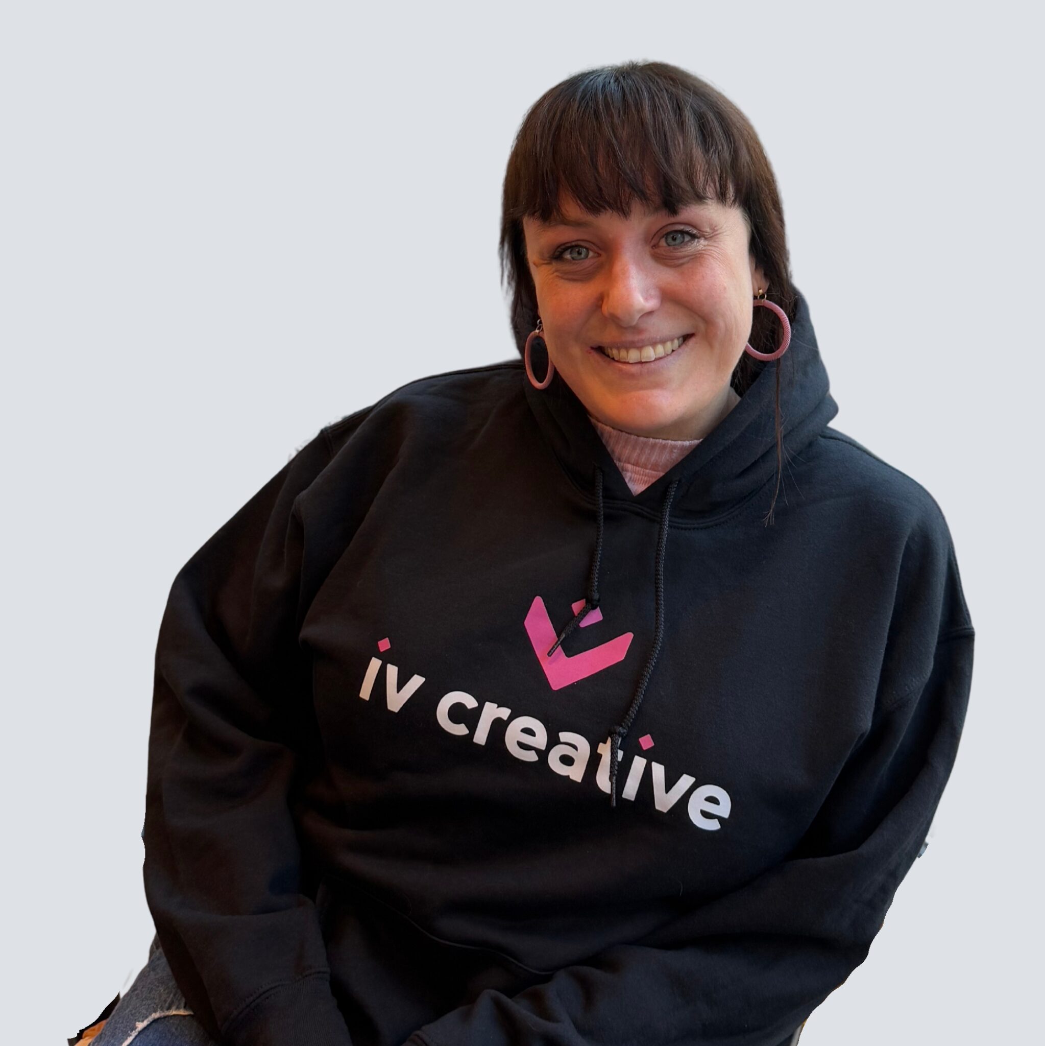 Portrait shot of woman in black IV Creative hoodie on a grey background.